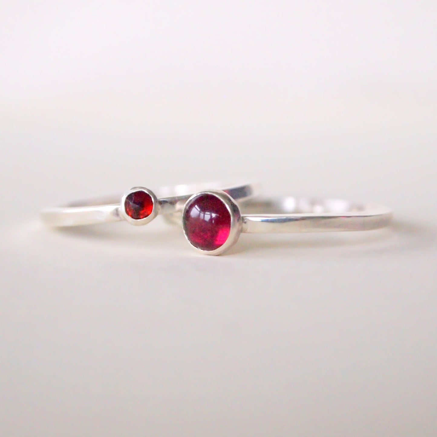 Sterling Silver double stacking ring set . One ring has a 5mm round garnet with the second having a smaller 3mm faceted stone. Handcrafted birthstone jewellery made in Scotland UK