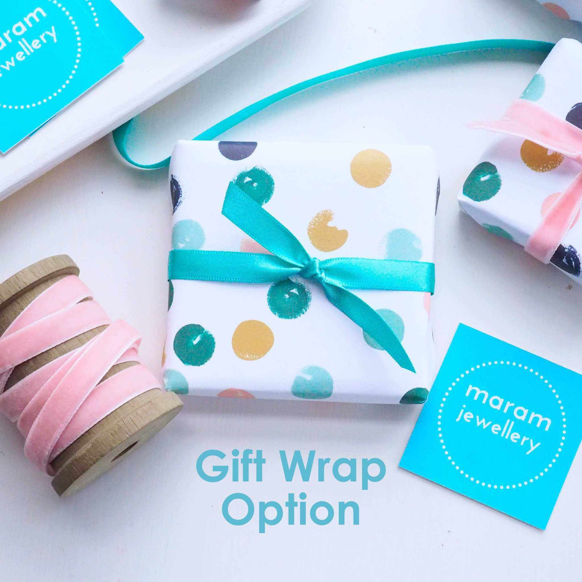 maram jewellery gift wrap option with text. Luxury dotty wrap tied with green ribbon pictured with velvet pink and green ribbon