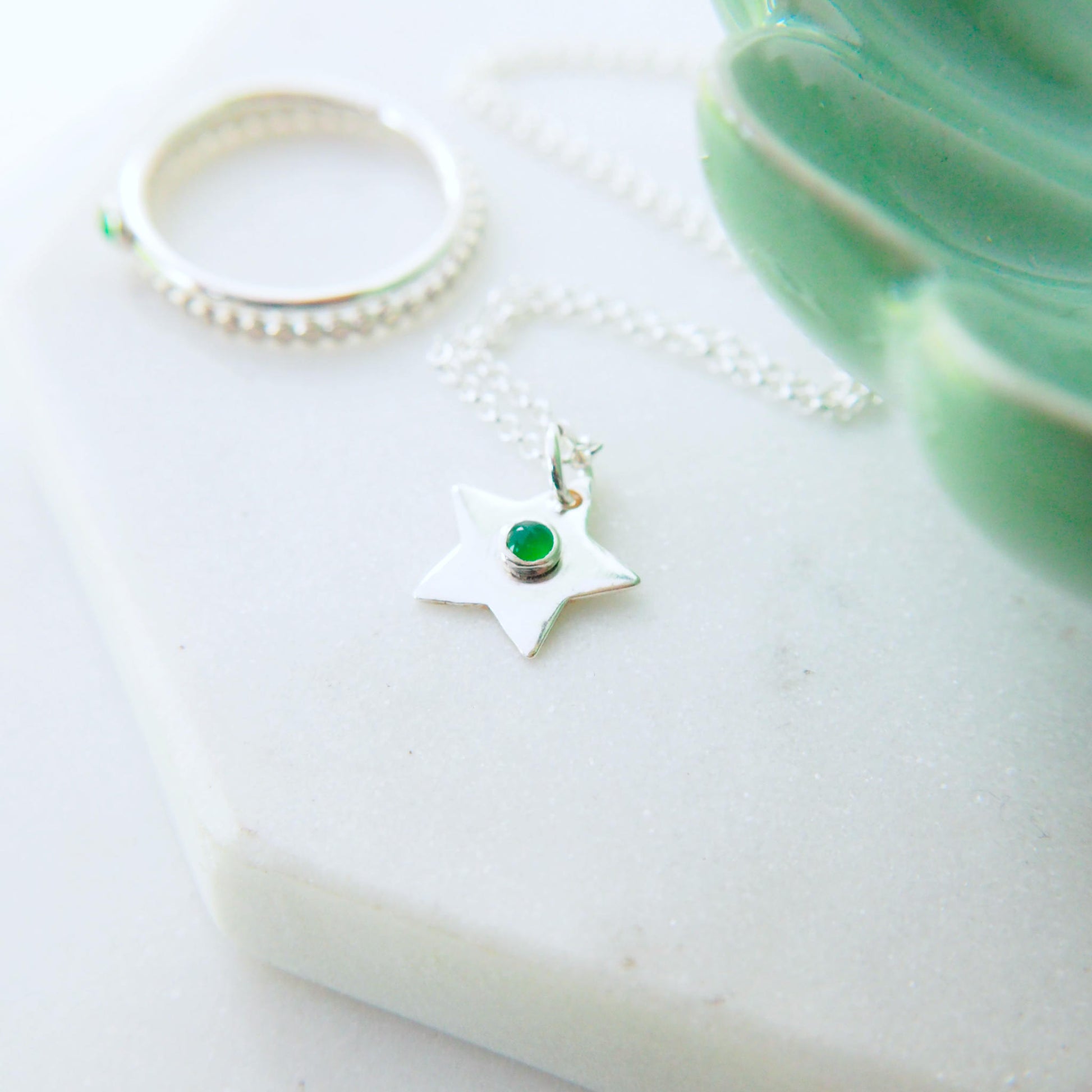 Birthstone Charm Necklace in the shape of a star with a round 3mm green agate cabochon centre. The star measures 12mm in size so is small enough for children as well as adults and is available in a range of other birthstones too. It is Sterling Silver and comes with a choice of chain design and length.The gemstone is Green Agate, Birthstone for May. Handmade in Scotland by Maram Jewellery
