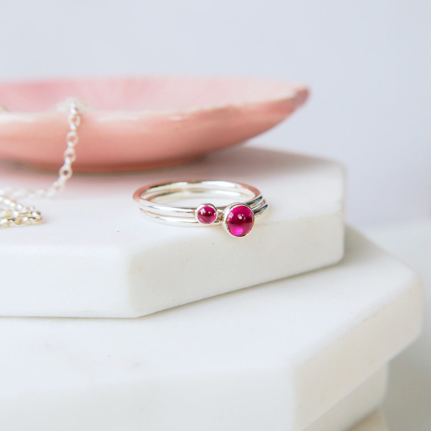 Two Silver rings with pink gemstones  in a 5mm and 3mm round shape and size on a white surface. Handcrafted by maram jewellery
