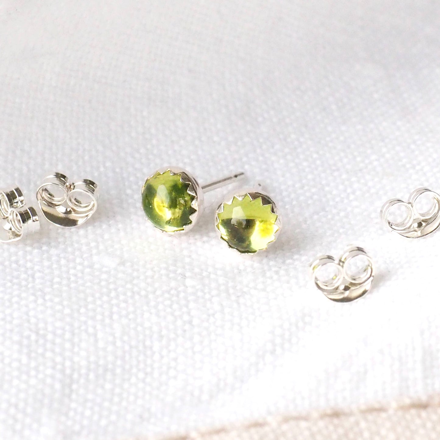 Peridot round gemstone studs with a peridot green cabochon gemstone in a simple silver setting. Handmade by maram jewellery in Scotland UK