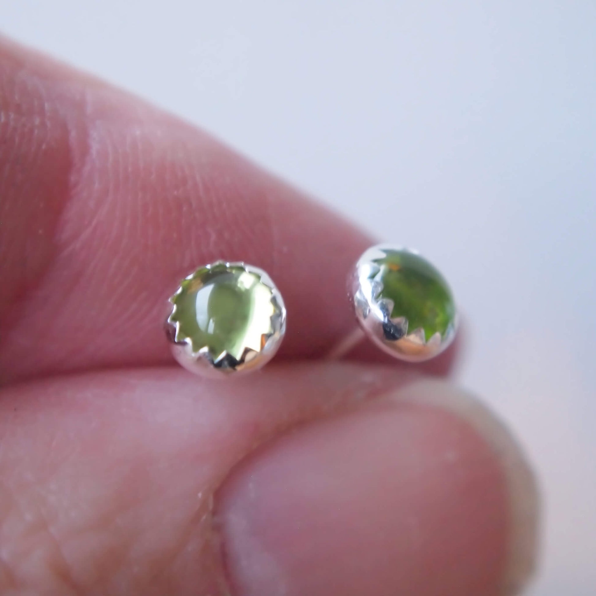 Peridot round gemstone studs with a peridot green cabochon gemstone in a simple silver setting. Handmade by maram jewellery in Scotland UK