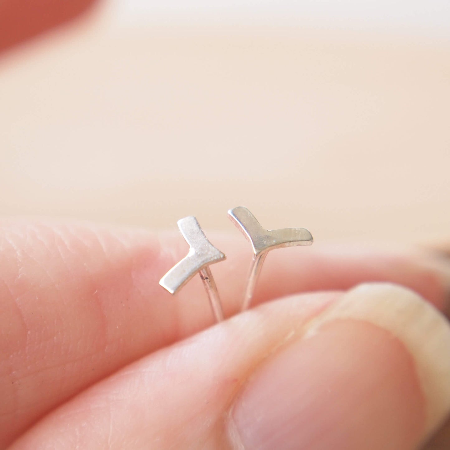 small chevron shape earrings in Sterling Silver shown held between two fingers to show their size - 6mm. The earrings are made by maram jewellery