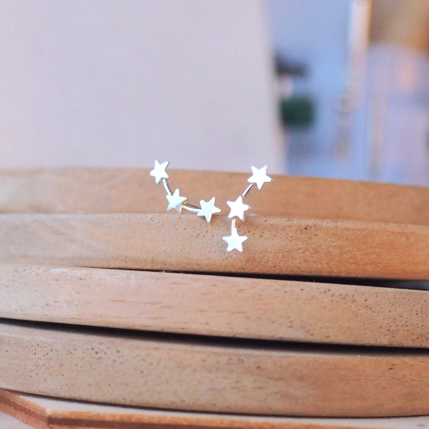 very simple star climber earrings amde from sterling silver with a row of three small silver stars on a thin wire like a star consolation.