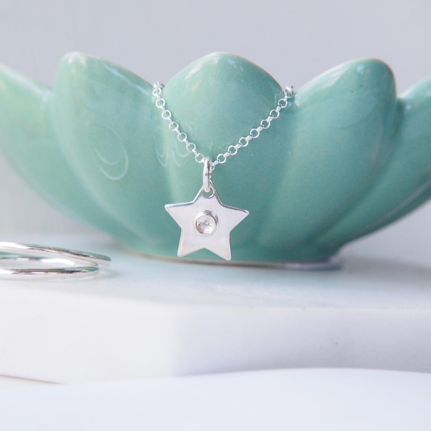 White topaz and silver star pendant on greem background by maram jewellery