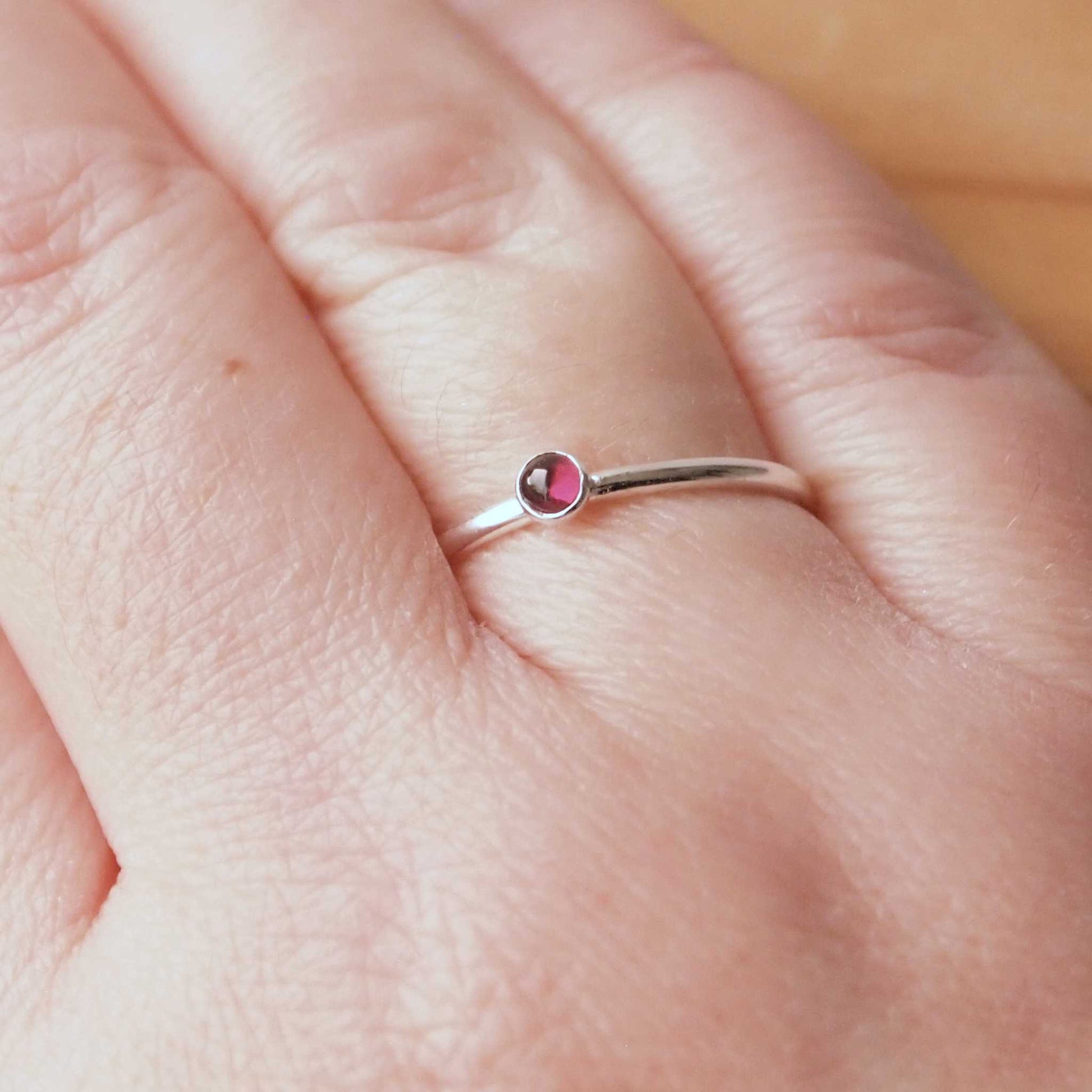 Small Garnet gemstone ring in sterling silver with a modern round band with a 3mm sized round dark red garnet, which is the birthstone for January. Handmade in Edinburgh by Maram Jewellery
