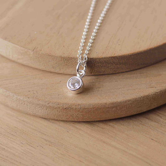 Petite Sterling Silver and Cubic Zirconia Diamond necklace with April Birthstone. A small 4mm faceted round clear imitation  diamond gemstone with a simple silver setting on a trace style chain. Handmade in Scotland by Maram Jewellery