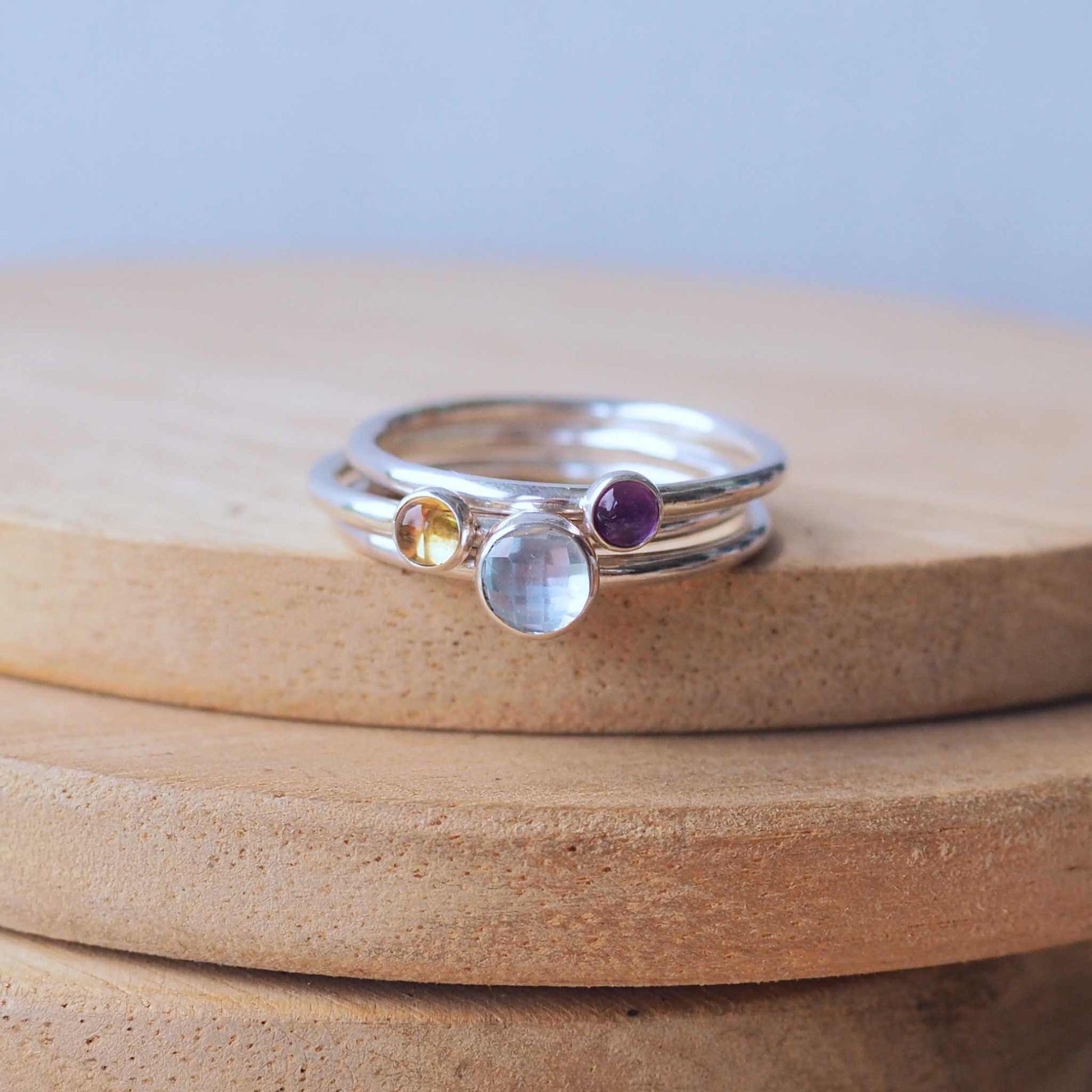 Three Birthstone RIng set with Blue Topaz, Amethyst and Citrine to mark March, February and November Birthdays. The three rings are made with Sterling SIlver and a 5mm blue round cabochon, with two further rings with 3mm round gems in a purple amethyst and yellow citrine. Handmade in Scotland by maram jewellery