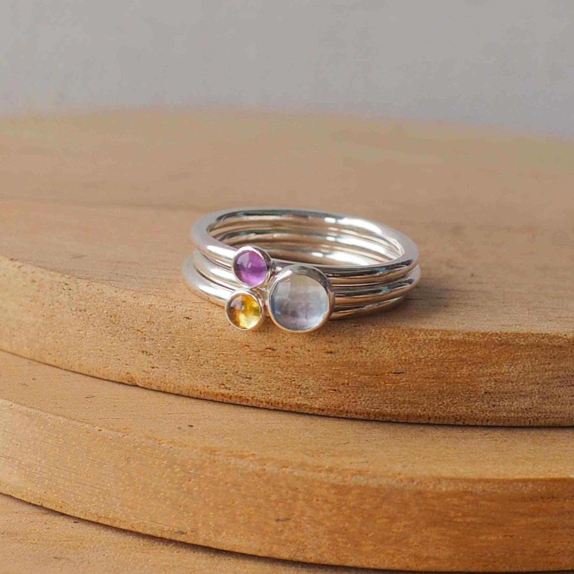 Three Birthstone Ring set with Blue Topaz, Amethyst and Citrine to mark March, February and November Birthdays. The three rings are made with Sterling SIlver and a 5mm blue round cabochon, with two further rings with 3mm round gems in a purple amethyst and yellow citrine. Handmade in Scotland by maram jewellery