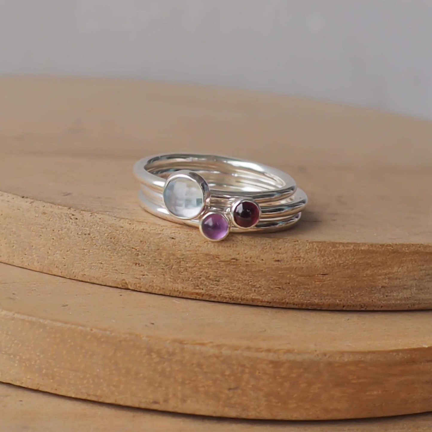 Three Birthstone Ring set with Blue Topaz, Garnet and Citrine to mark March, January and February Birthdays. The three rings are made with Sterling Silver and a 5mm blue round cabochon, with two further rings with 3mm round gems in a deep red garnet and purple Amethyst. Handmade in Scotland by maram jewellery