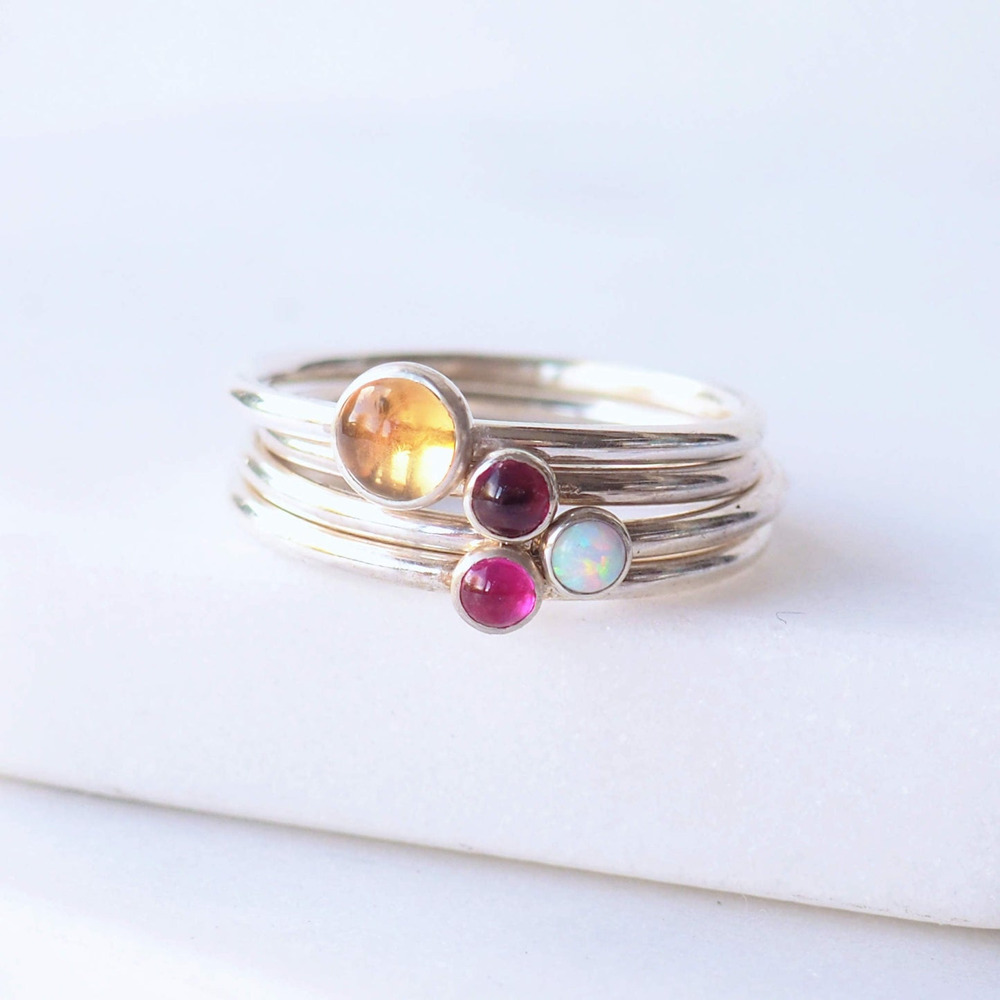 Four Silver birthstone rings with a large round Yellow Citrine for November with three additional birthstone rings of your choice, picture shows deep red garnet, pink lab ruby and white lab opal. Handmade by maram jewellery in Scotland UK