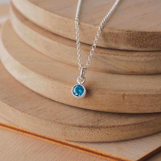 Petite Sterling Silver and Cubic Zirconia Blue Zircon necklace with December Birthstone. A small 4mm facet round rich blue gemstone with a simple silver setting on a trace style chain. Handmade in Scotland by Maram Jewellery