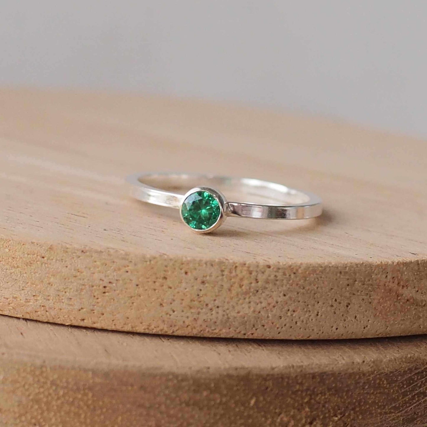 Silver ring with a Green gemstone. The ring is simple in style with no embellishment , with a round wire band 1.5mm thick with a simple Green Emerald 4mm round cubic zirconia stone set in an enclosed silver setting. Emerald is birthstone for May. The ring is Sterling Silver and made to your ring size. Handmade in Scotland by Maram Jewellery