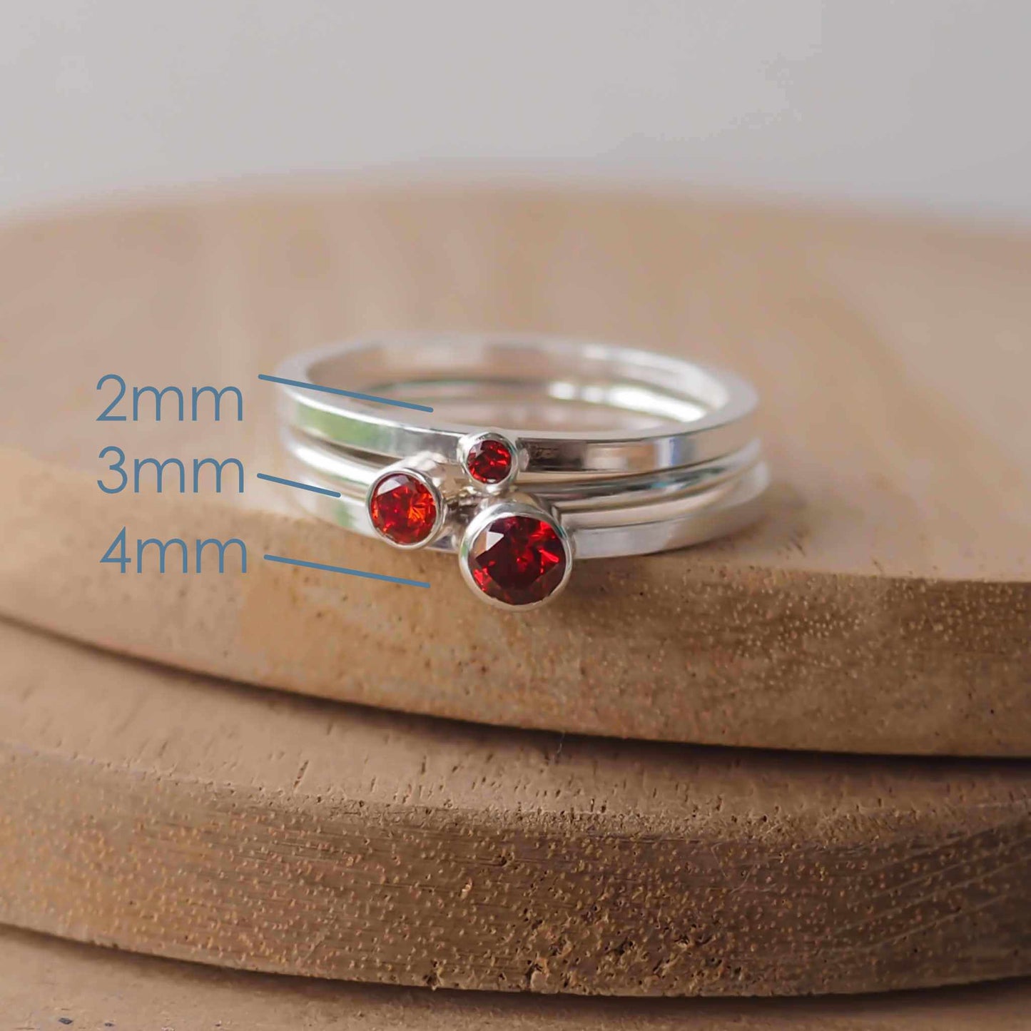 Three rings showing the square and round band styles with three different sized Cubic Zirconia in a deep red Garnet. The rings are made from Sterling Silver and a round red cubic zirconia measuring 2,3 or 4mm in size. Handmade by maram jewellery in Scotland