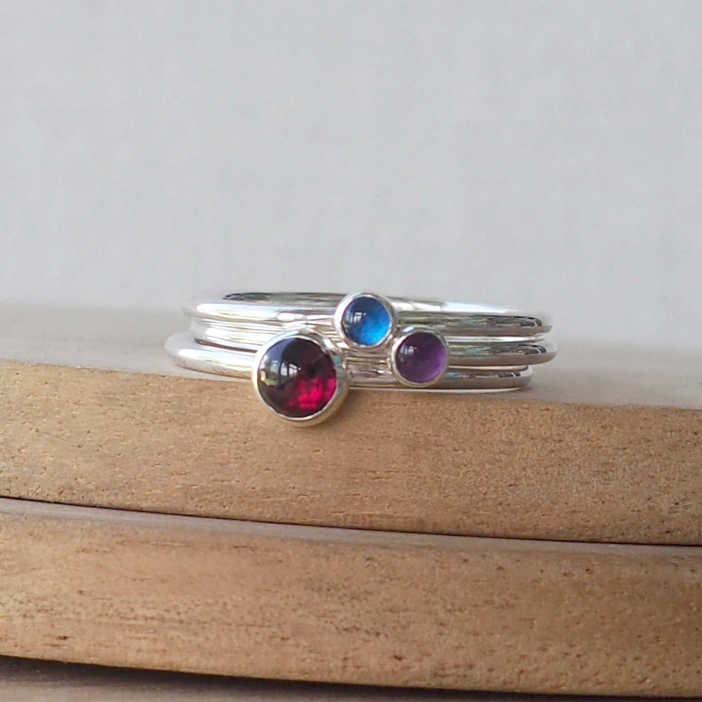 three ring set with your choice of birthstone Birthstones. THis set has a January birthstone ring with a 5mm round dark red cabochon smooth cut stone, A sapphire 3mm stone for September and a 3mm round purple amethyst for February. Handmade in Edinburgh by Maram Jewellery