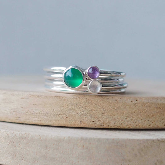 Three Birthstone Ring set made from Sterling Silver, with a 5mm round Green Agate Birthstone for May, and two smaller 3mm gemstones in Moonstone for June and Amethyst for February. The gemstones colours are emerald green, purple and milky white. Handmade in Scotland by Maram Jewellery
