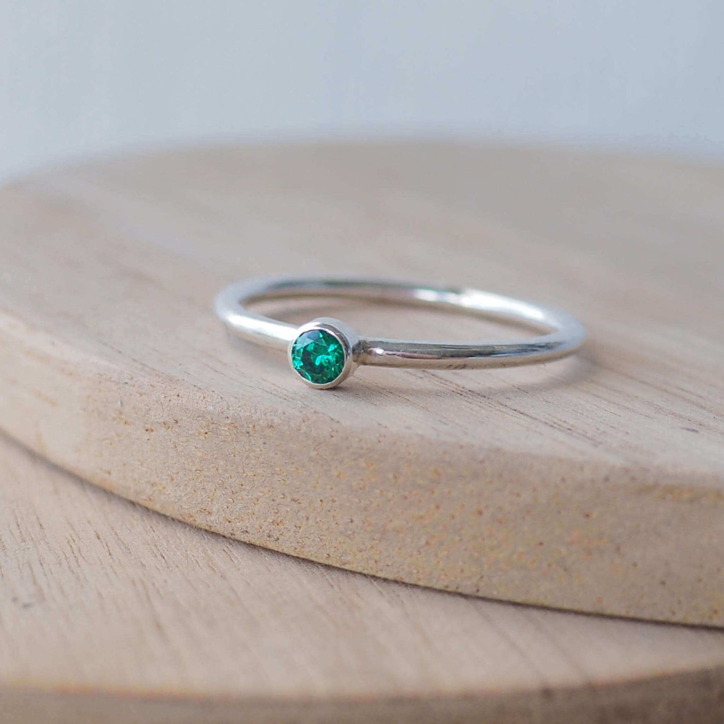 Silver ring with a Green gemstone. The ring is simple in style with no embellishment , with a round wire band 1.5mm thick with a simple Green Emerald 2mm round cubic zirconia stone set in an enclosed silver setting. The gem is very small and minimal on the band Emerald is birthstone for May. The ring is Sterling Silver and made to your ring size. Handmade in Scotland by Maram Jewellery