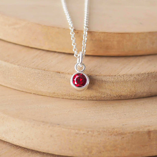 Small Sterling Silver and Cubic Zirconia Red necklace. A small 4mm facet round rich red gemstone with a simple silver setting on a trace style chain, suitable as a January Garnet  or July Ruby Birthstone charm . Handmade in Scotland by Maram Jewellery