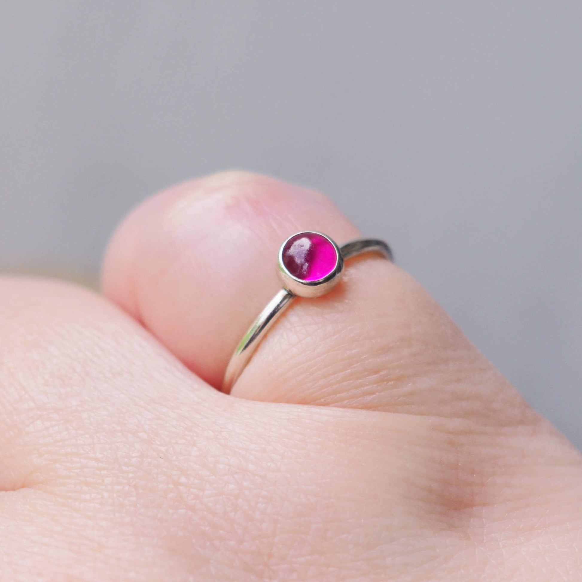 Single Solitaire simple style Sterling SIlver and A Lab Ruby pink Cabochon ring. The lab ruby gemstone is round and measure 5mm and it's set onto a band of fully round wire. It can be made to measure in any size. Handmade in Scotland by Maram Jewellery