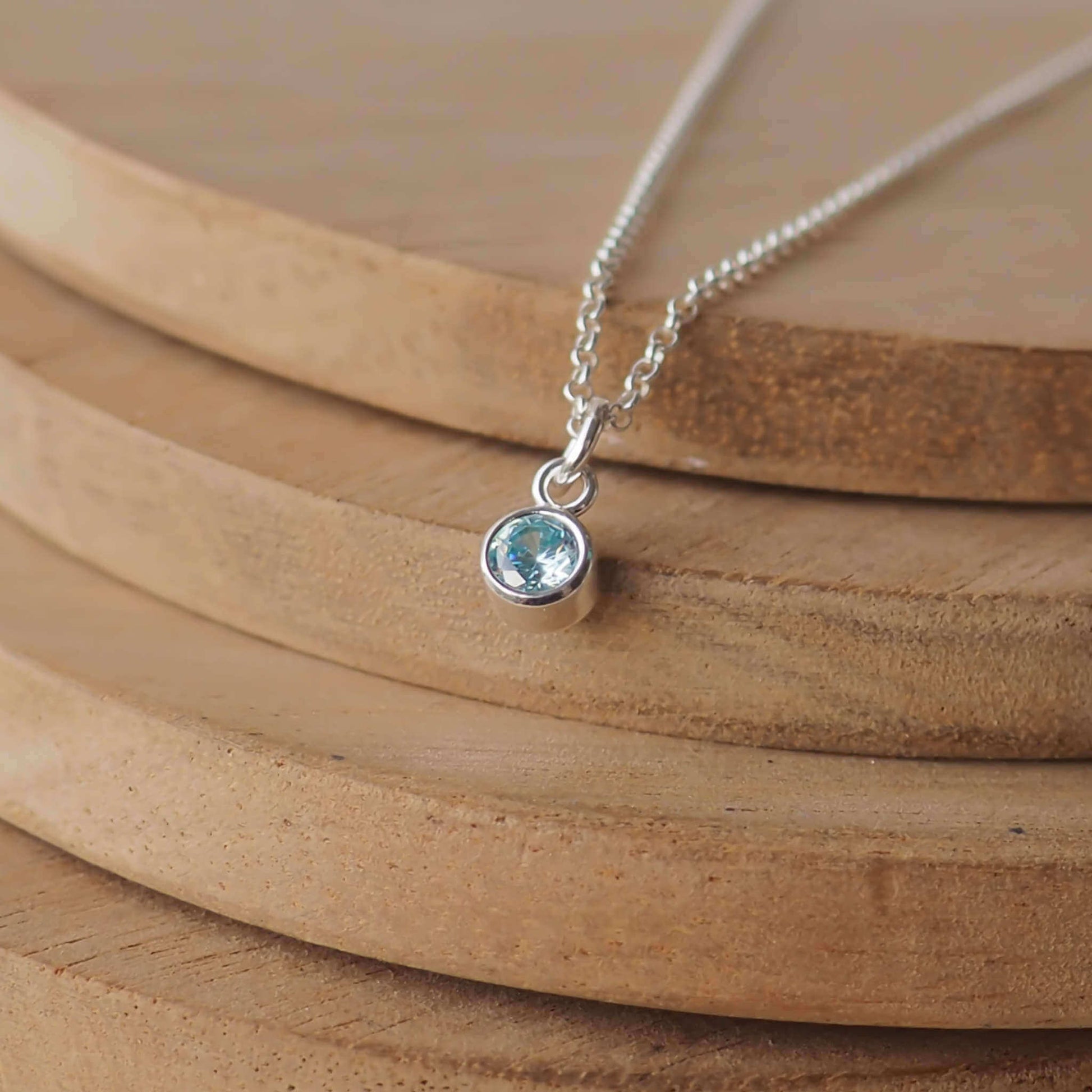 Petite Sterling Silver and Cubic Zirconia Aquamarine necklace with March Birthstone. A small 4mm faceted round pale blue gemstone with a simple silver setting on a trace style chain. Handmade in Scotland by Maram Jewellery