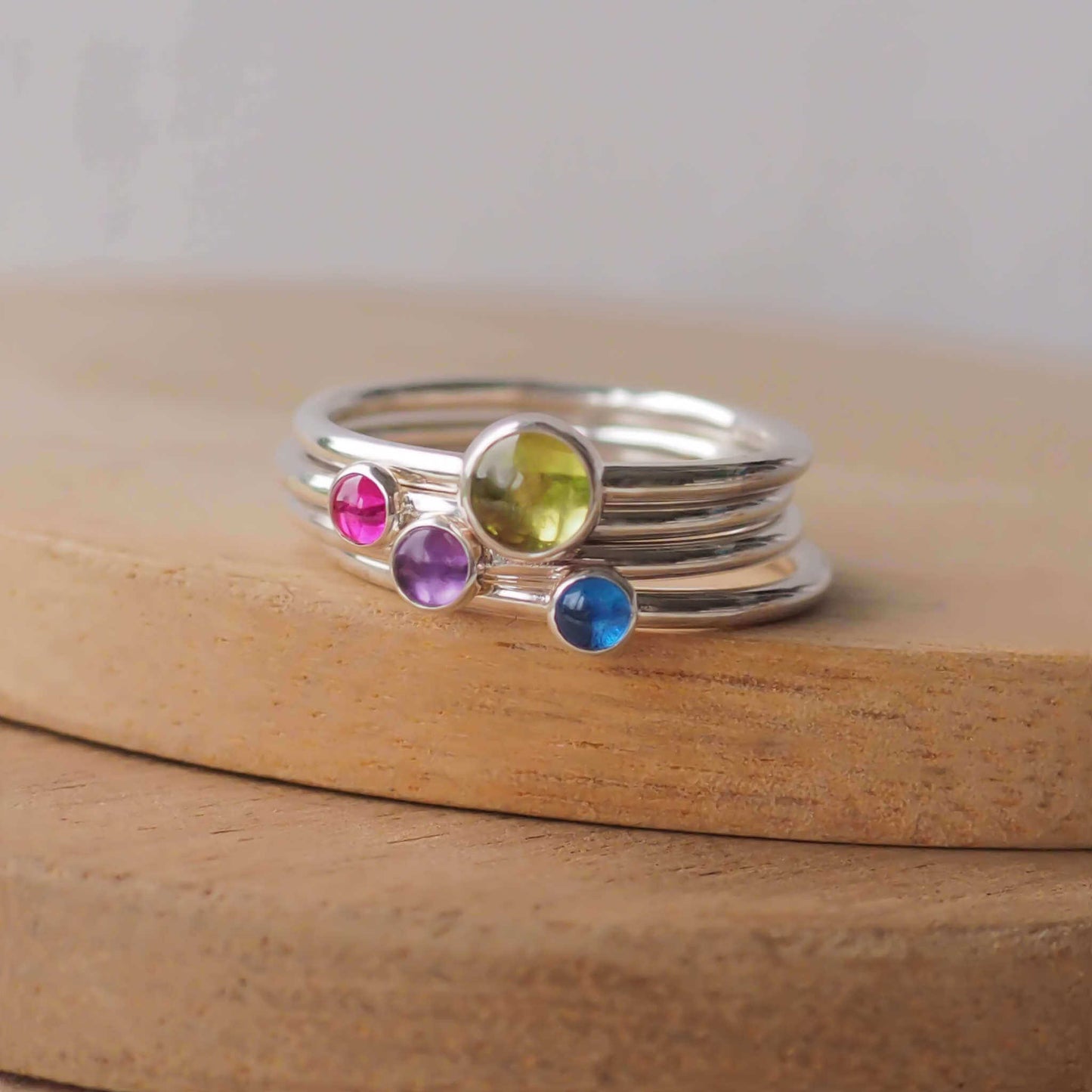 Four rings in Sterling Silver and mixed gemstones. The rings are minimalist in style with no decoration and feature a single simple round cabochon in a large 5mm Moss Green Peridot, smaller 3mm pink Lab Ruby, Purple Amethyst, and bright Blue Lab Sapphire. Handmade in Scotland by maram jewellery