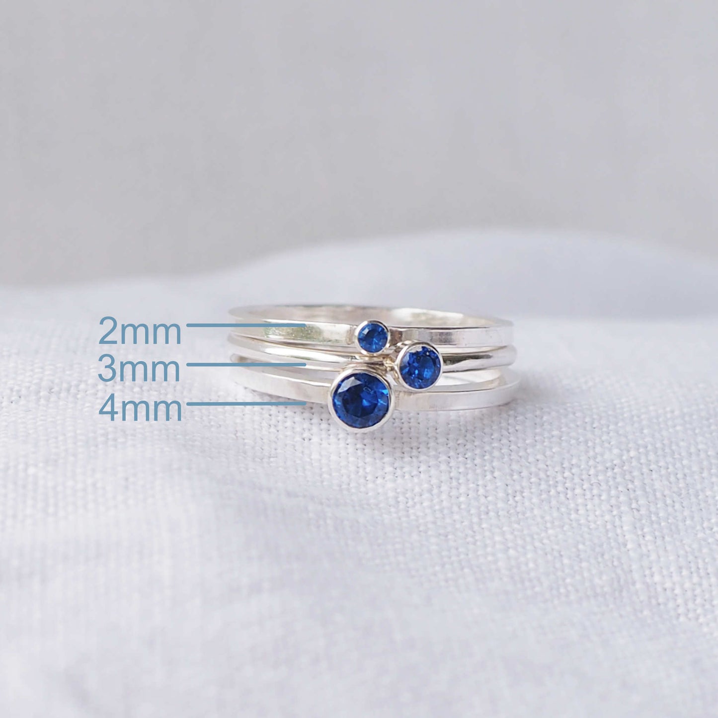 Three rings showing the square and round band styles with three different sized Cubic Zirconia in a Blue Sapphire colour. The rings are made from Sterling Silver and a round blue cubic zirconia measuring 2,3 or 4mm in size. Handmade by maram jewellery in Scotland