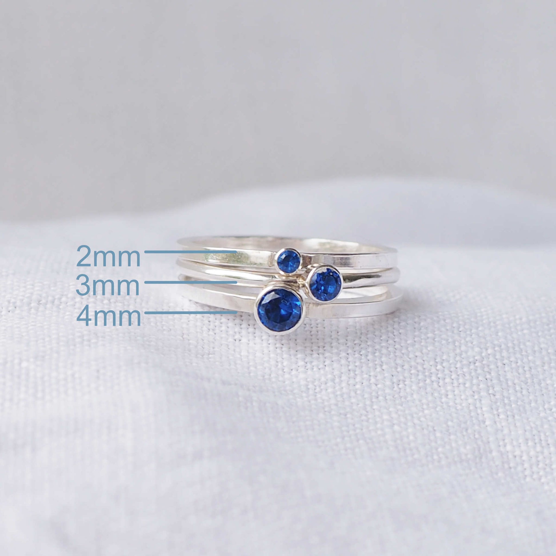 Three rings showing the square and round band styles with three different sized Cubic Zirconia in a Blue Sapphire colour. The rings are made from Sterling Silver and a round blue cubic zirconia measuring 2,3 or 4mm in size. Handmade by maram jewellery in Scotland