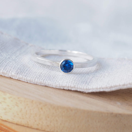 Sapphire Blue solitaire ring in a modern style with a simple square band, The ring is made from Sterling Silver and Bright Blue Cubic zirconia with a 4mm round gemstone fully enclosed in a silver setting. Handmade by maram jewellery in Edinburgh