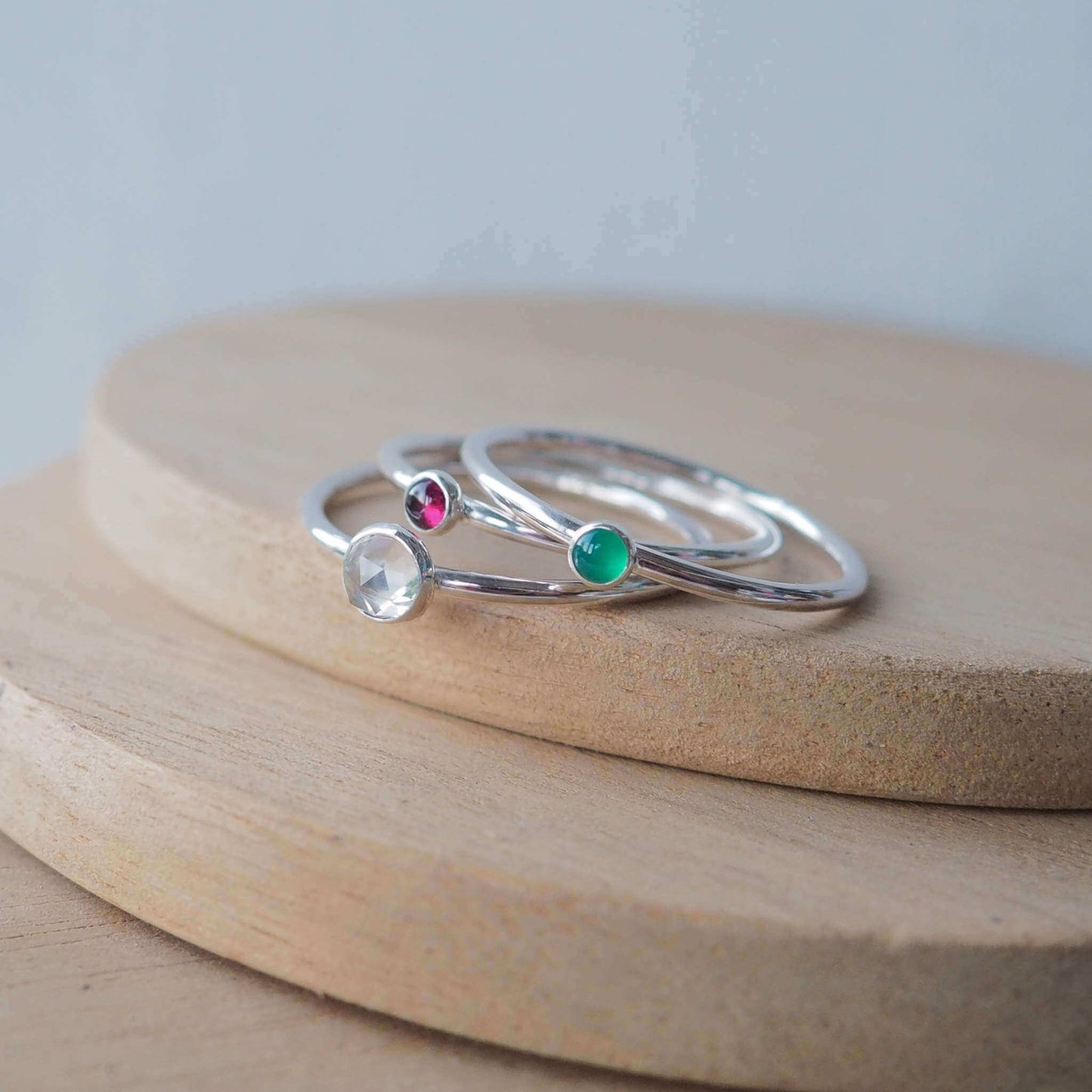 Three Silver Ring Birthstone set with April, January and May Birthstones. The set has three round cabochon stones, a 5mm round faceted clear white topaz, a 3mm green agate and a 3mm dark red garnet. Handmade in Scotland by Maram Jewellery