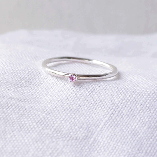 Silver ring with a light purple gemstone. The ring is simple in style with no embellishment , with a round wire band 1.5mm thick with a simple Lavender Alexandrite 2mm round cubic zirconia stone set in an enclosed silver setting. The gem is very small and minimal on the band. Alexandrite is birthstone for June. The ring is Sterling Silver and made to your ring size. Handmade in Scotland by Maram Jewellery