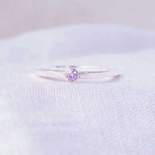 Silver ring with a lavender Alexandrite gemstone. The ring is simple in style with no embellishment , with a square wire band 1.5mm thick with a simple pale purple 3mm round cubic zirconia stone set in an enclosed silver setting. Alexandrite is birthstone for June. The ring is Sterling Silver and made to your ring size. Handmade in Scotland by Maram Jewellery