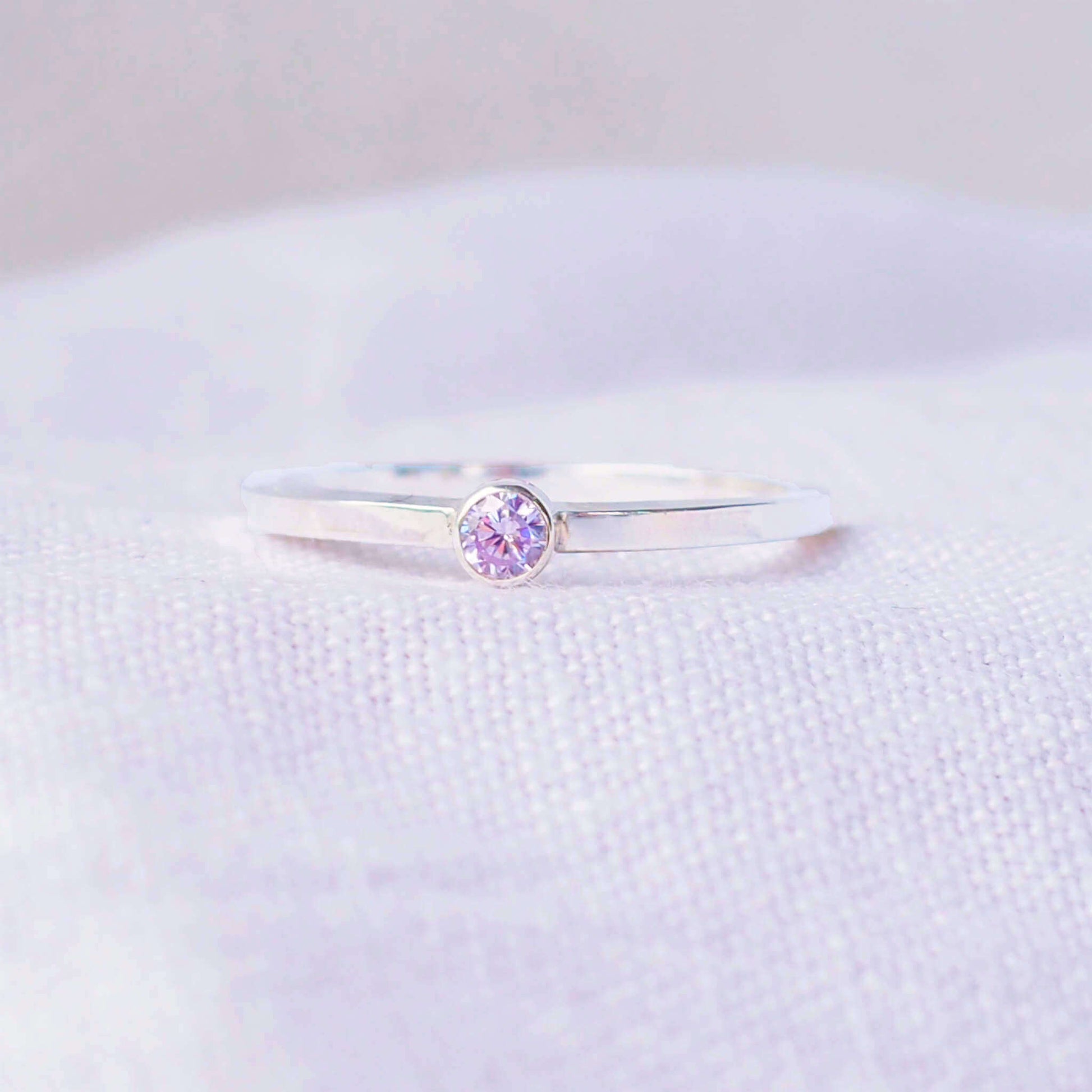 Silver ring with a lavender Alexandrite gemstone. The ring is simple in style with no embellishment , with a square wire band 1.5mm thick with a simple pale purple 3mm round cubic zirconia stone set in an enclosed silver setting. Alexandrite is birthstone for June. The ring is Sterling Silver and made to your ring size. Handmade in Scotland by Maram Jewellery