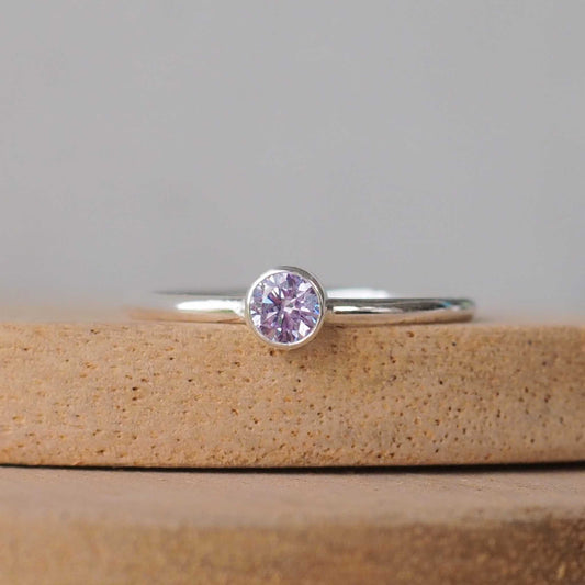 Silver ring with a Lavender Cubic Zirconia gemstone. The ring is simple in style with no embellishment , with a round wire band 1.5mm thick with a simple light purple alexandrite substitute 4mm round cubic zirconia stone set in an enclosed silver setting. Birthstone for June. The ring is Sterling Silver and made to your ring size. Handmade in Scotland by Maram Jewellery