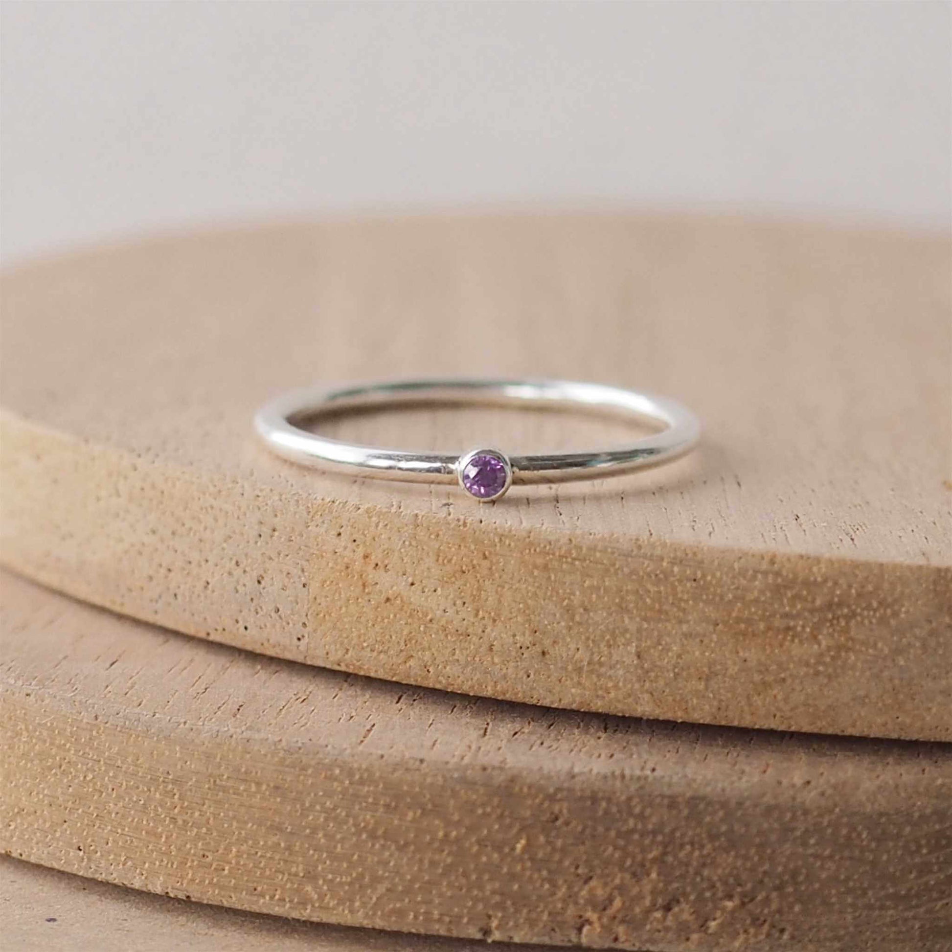 Silver ring with a purple gemstone. The ring is simple in style with no embellishment , with a round wire band 1.5mm thick with a simple purple 2mm round cubic zirconia stone set in an enclosed silver setting. Amethyst is birthstone for February. The ring is Sterling Silver and made to your ring size. Handmade in Scotland by Maram Jewellery