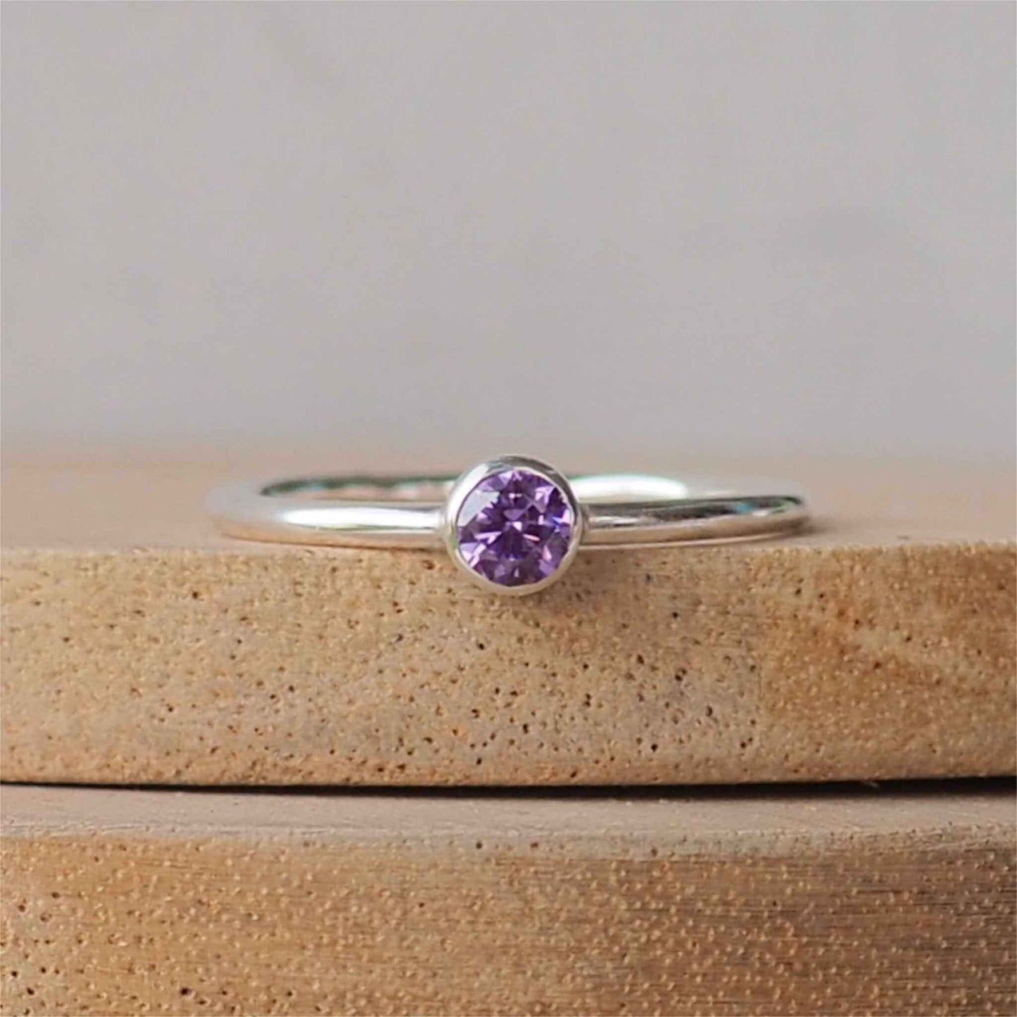 Sparkly Purple and silver gemstone ring made from amethyst Cubic zirconia and Sterling Silver. THe ring in very simple in style with a 4mm round gemstone set in a silver surround on a modern halo band. Handmade in Scotland by maram jewellery