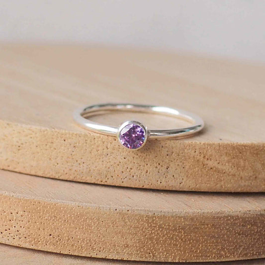 Silver ring with a Purple gemstone. The ring is simple in style with no embellishment , with a round wire band 1.5mm thick with a simple Deep Purple Amethyst  4mm round cubic zirconia stone set in an enclosed silver setting. Amethyst is birthstone for February. The ring is Sterling Silver and made to your ring size. Handmade in Scotland by Maram Jewellery