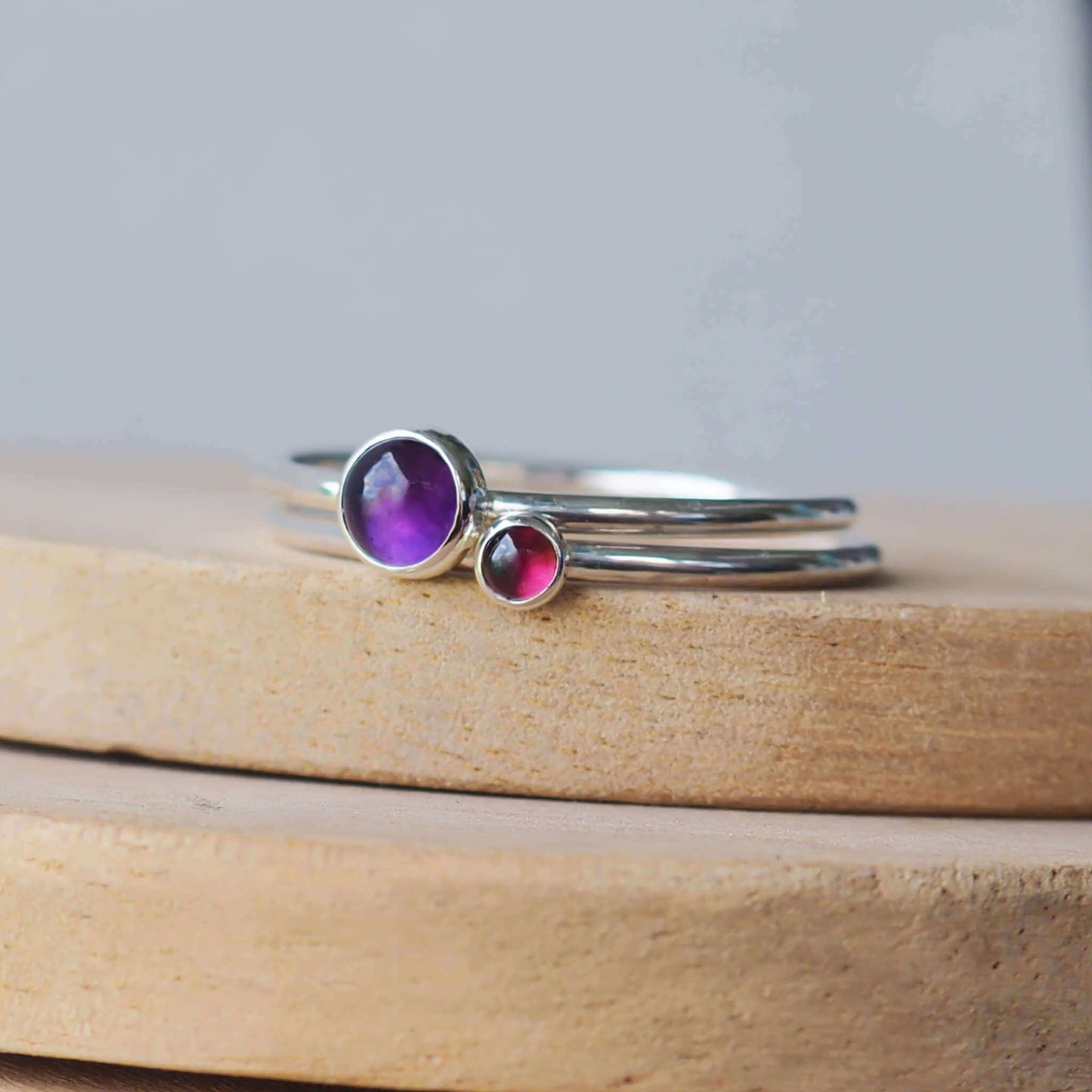 Double Ring set in Sterling Silver and gemstones in purple and red, The rings have two round gemstones of 5mm and 3mm size and are set simply onto round bands of sterling silver. These are February and January's birthstone and are hand made to your ring size by maram jewellery in Scotland