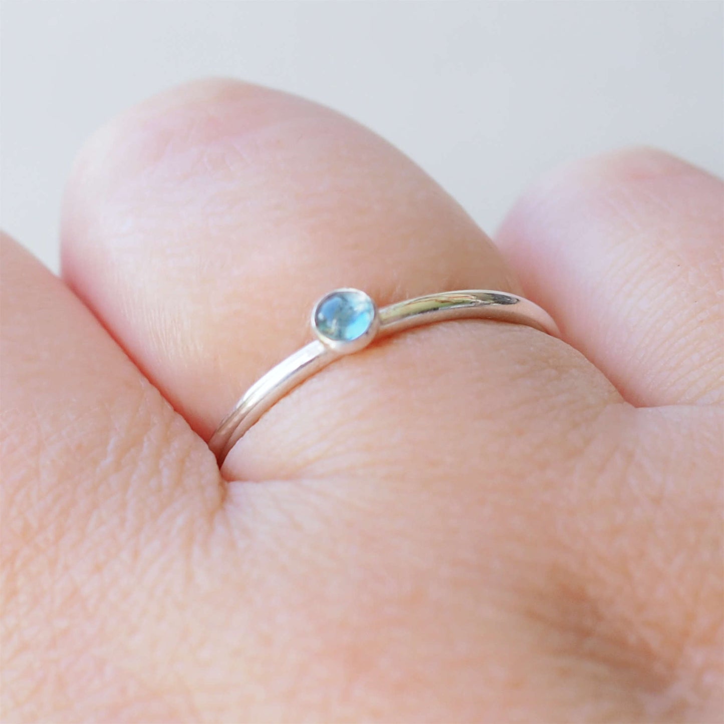Small gemstone ring in sterling silver with a modern round band with a 3mm sized round light blue Aquamarine. Handmade in Edinburgh by Maram Jewellery