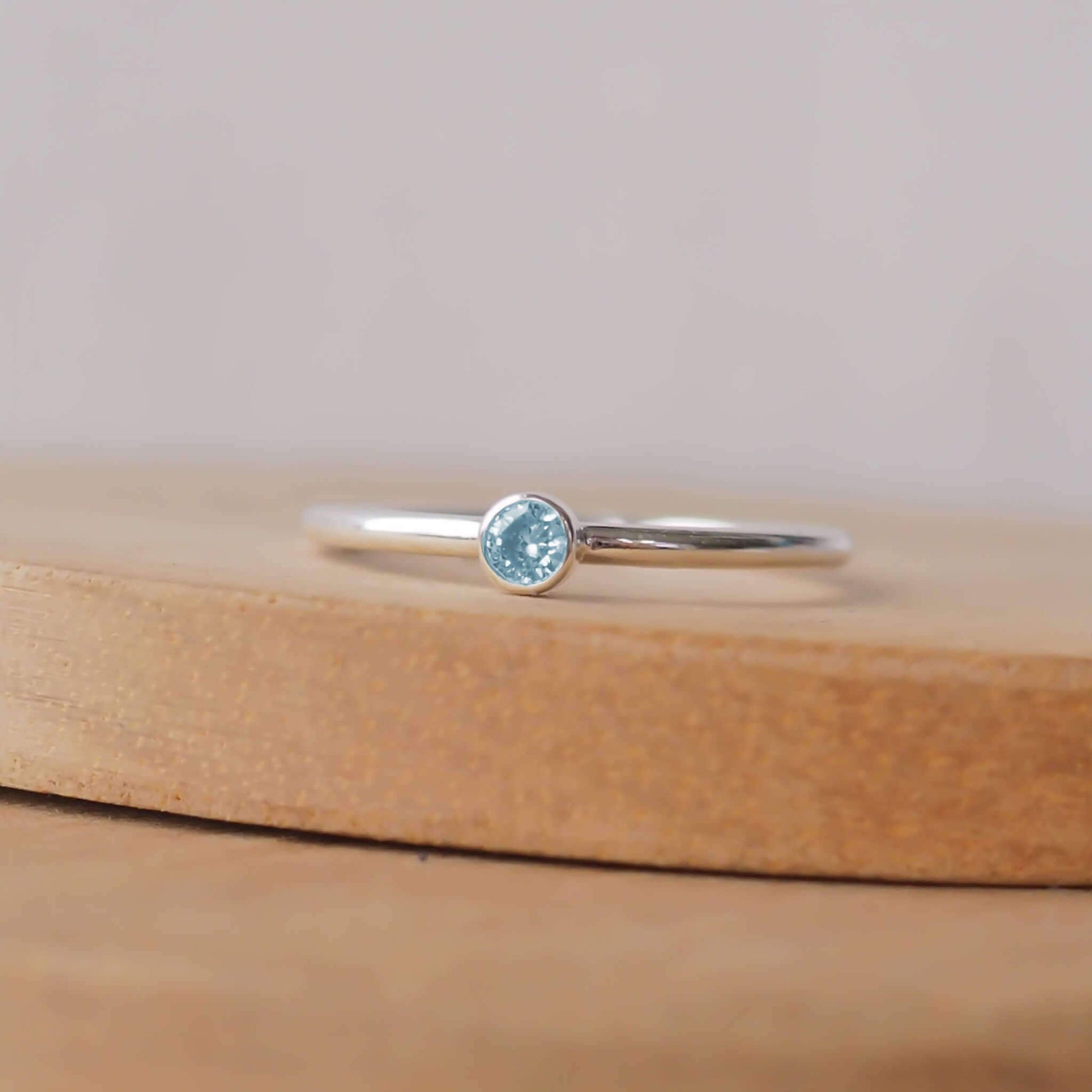 Aquamarine and Sterling Silver solitaire ring with an aqua coloured round cubic zirconia measuring 3mm in size. A very simple minimalist ring made from Sterling Silver on a halo style band. Handmade in Scotland by maram jewellery