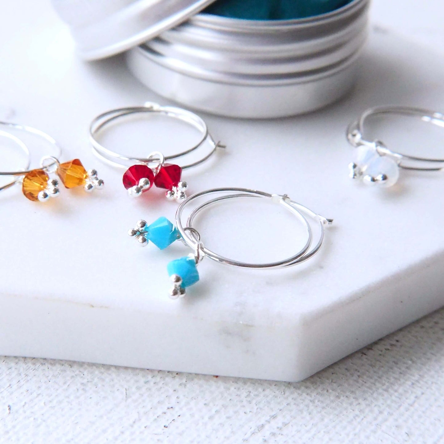 Birthstone hoops with wire hoops and a birthstone crystal pictured on a white marble background with December Turquoise, November Citrine January Garnet and October Opal variations. Handmade by maram jewellery in Scotland