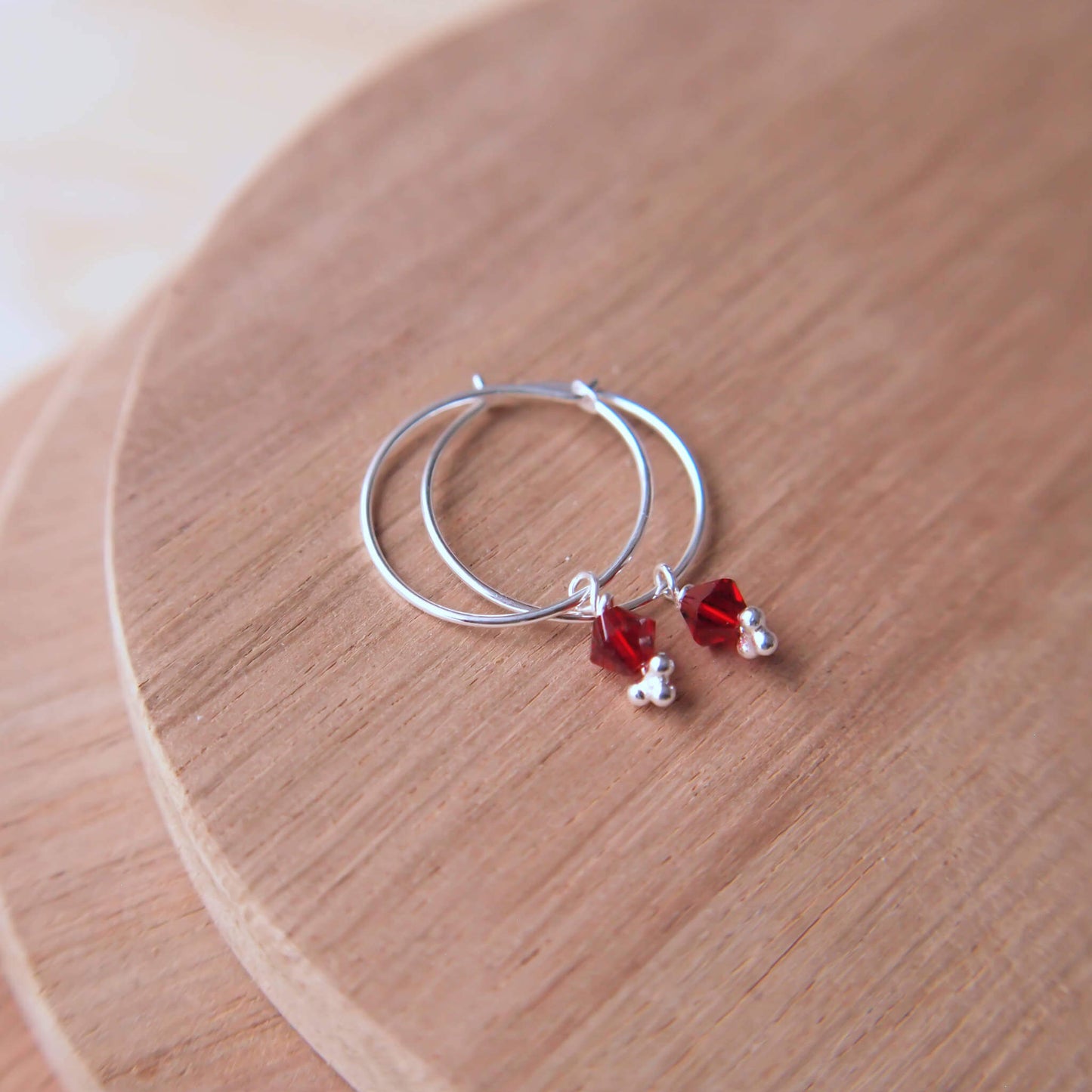 Simple Birthstone crystal hoops in garnet red. Boho style jewellery made from a thin sterling silver hoop with a single birthstone crystal for January. Made in a small studio in Scotland UK