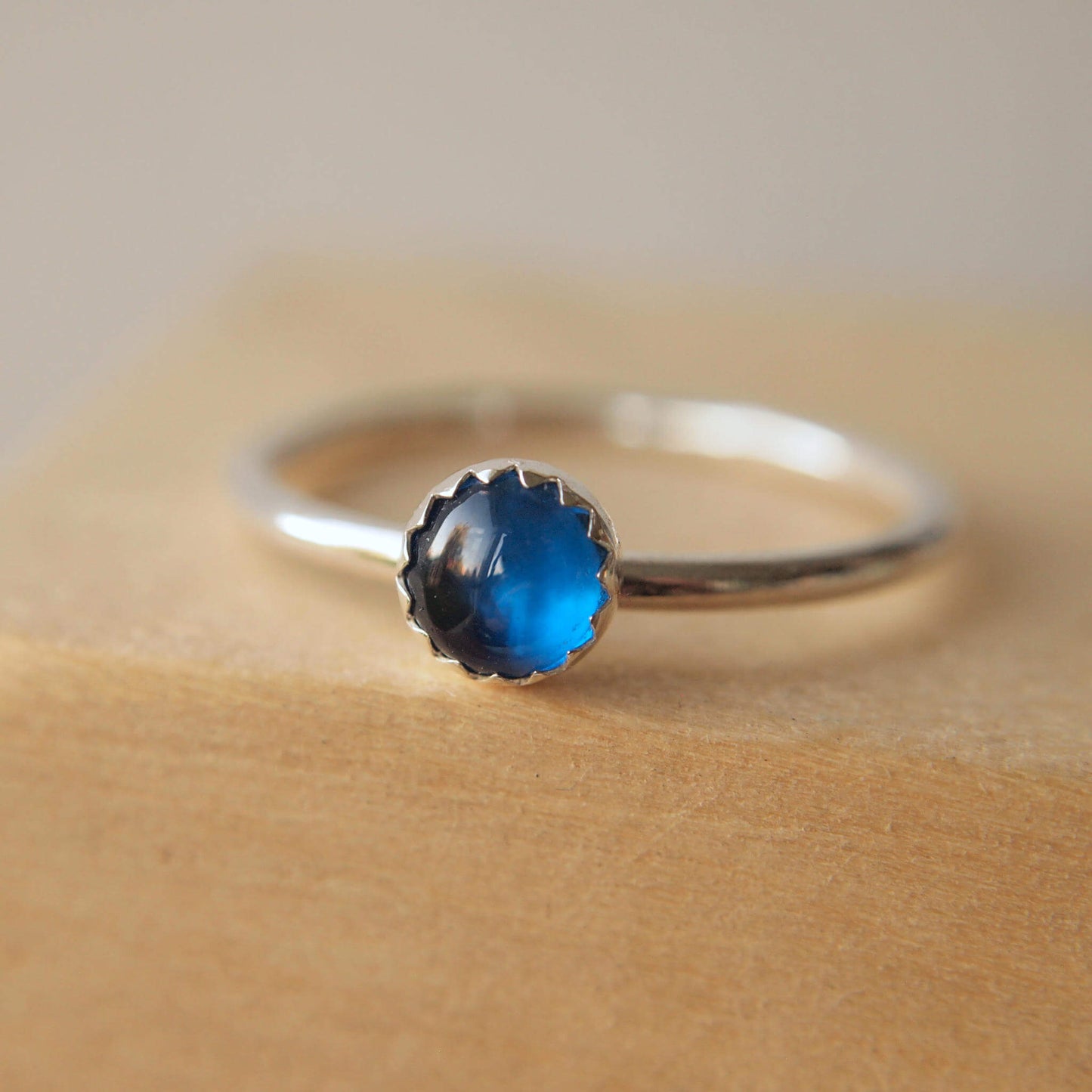 Simple styled silver and blue gemstone ring with a lab sapphire round stone on a silver band. The ring is made from a 5mm round cabochon in bright blue. Handmade to your choice of ring size by maram jewellery in Scotland