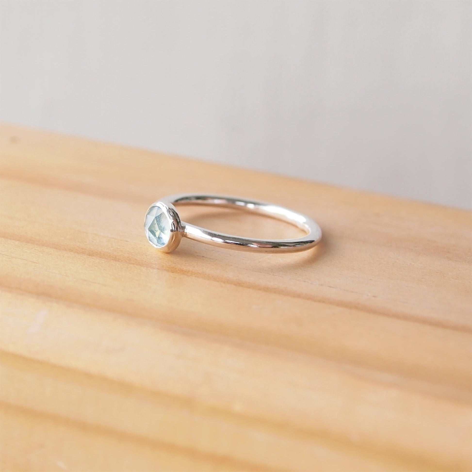 Simple Silver and aquamarine ring with a 5mm round light aqua facet cut cabochon set simply on a round band. Birthstone for March. Handmade by Maram Jewellery in Scotland