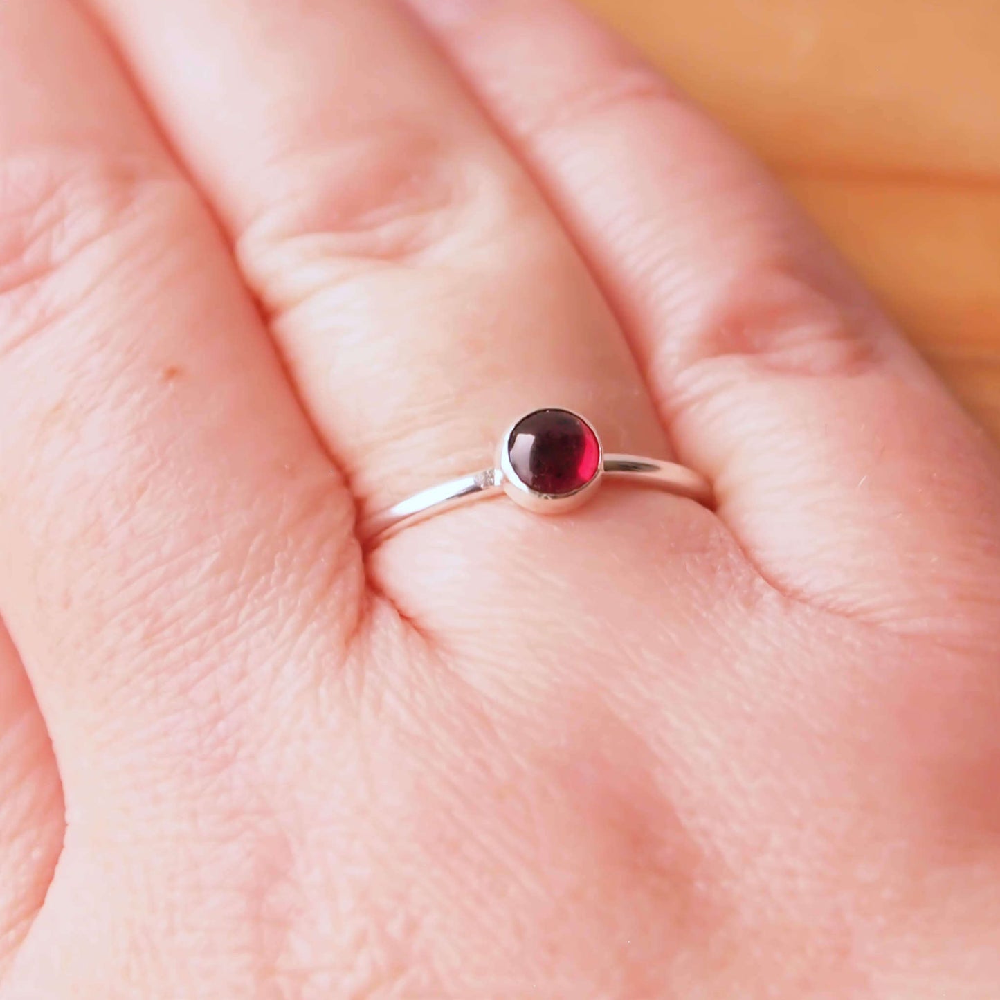 Garnet and Sterling Silver January Birthstone Ring. a 5mm round deep red garnet cabochon set very simply onto a round band of sterling silver. handmade by maram jewellery in Scotland