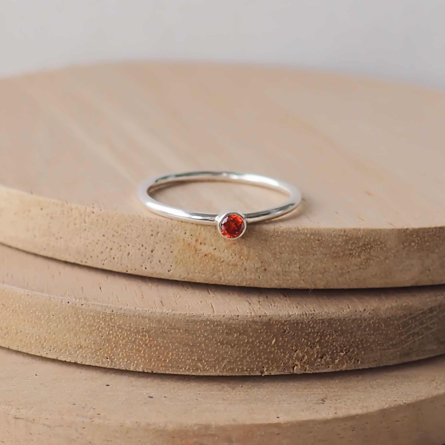 Garnet red solitaire ring in a modern style with a simple round band, The ring is made from Sterling Silver and red Cubic zirconia with a 3mm round gemstone fully enclosed in a silver setting. Handmade by maram jewellery in Edinburgh