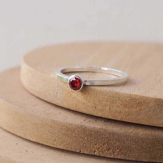 Garnet and Sterling Silver solitaire ring with a deep red coloured round cubic zirconia measuring 4mm in size. A very simple minimalist ring made from Sterling Silver on a minimalist square style band.Garnet is the birthstone for January. Handmade in Scotland by maram jewellery