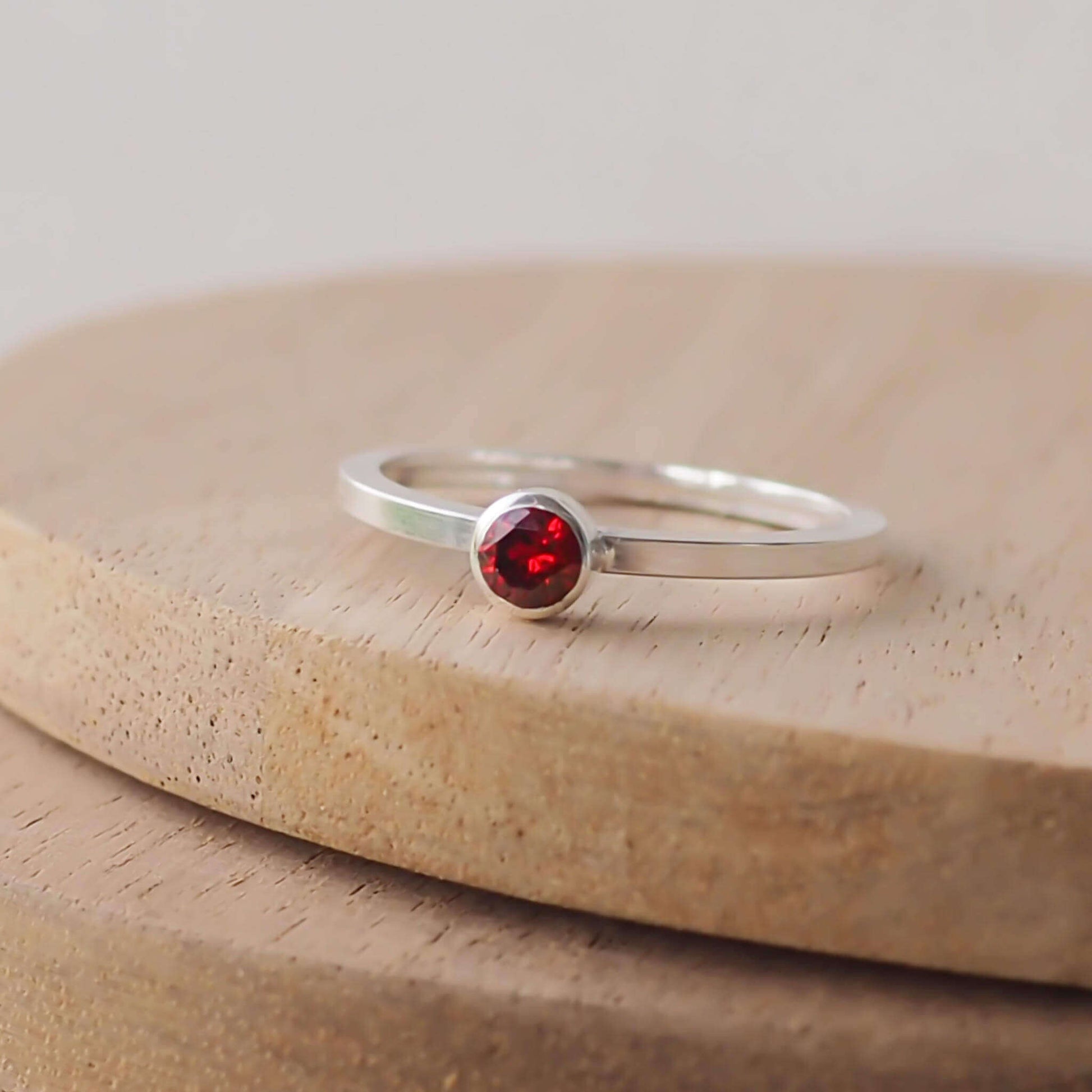 Garnet and Sterling Silver solitaire ring with a deep red coloured round cubic zirconia measuring 4mm in size. A very simple minimalist ring made from Sterling Silver on a minimalist square style band.Garnet is the birthstone for January. Handmade in Scotland by maram jewellery