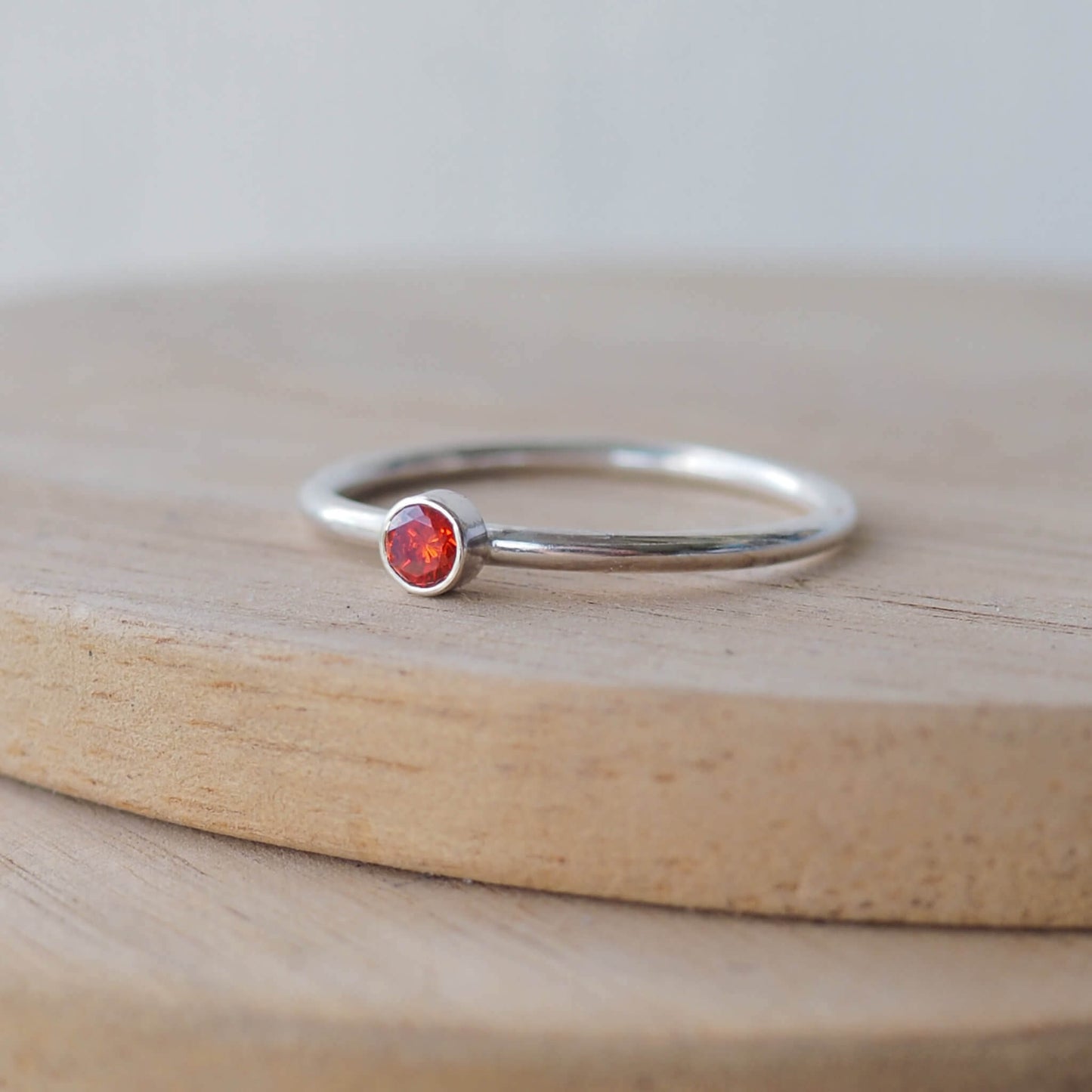 Garnet and silver minimalist solitaire ring. Made from a modern band of square silver wire with a simple round  red faceted cubic zirconia. Handmade in Scotland by Maram Jewellery