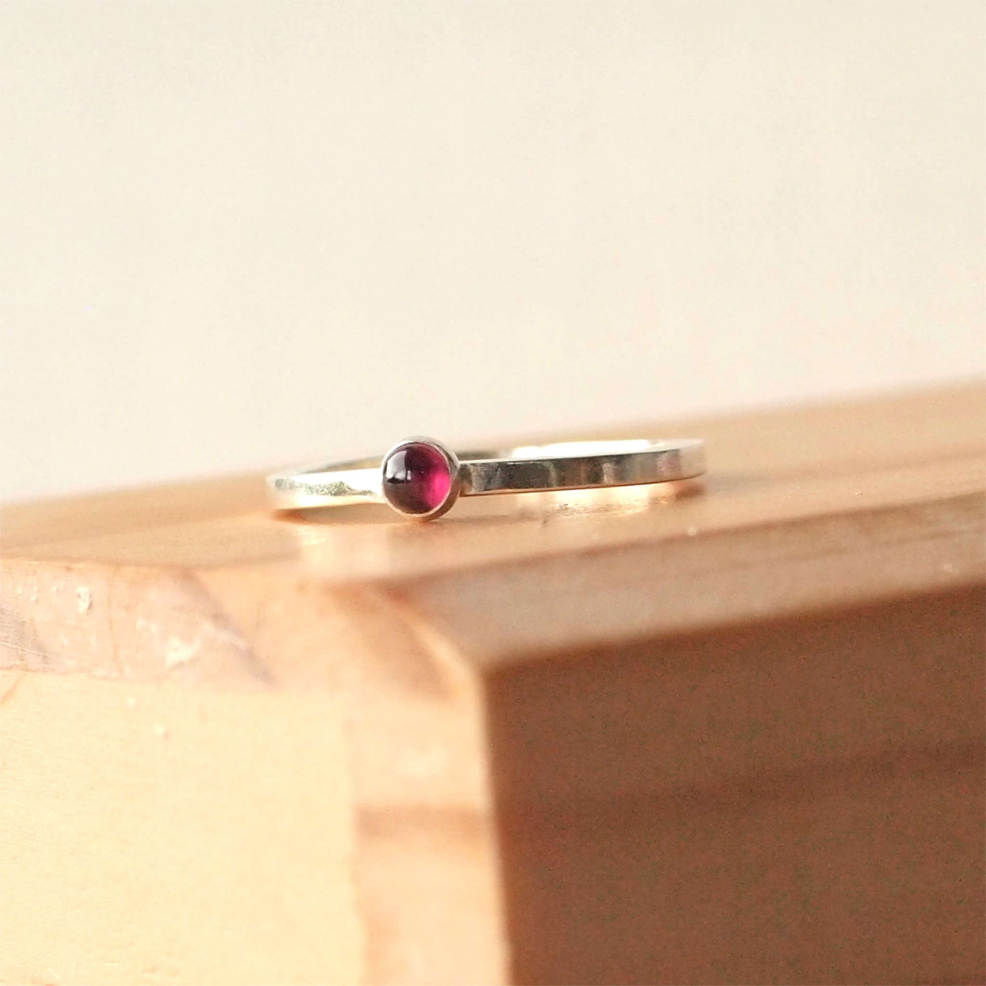 Simple Silver and Garnet ring with a 3mm round deep red cabochon set simply on a round band. Birthstone for January. Handmade by Maram Jewellery in Scotland