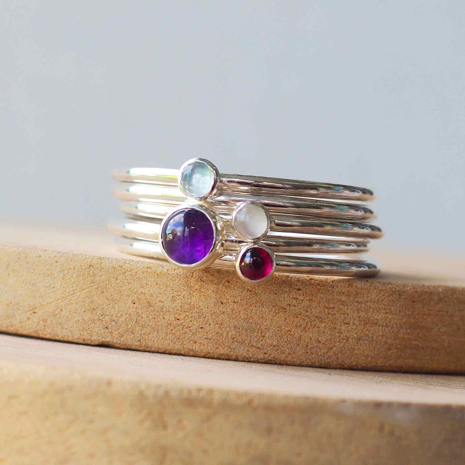 Four ring set in Sterling Silver and mixed gemstones. The rings are minimalist in style with no decoration and feature a single simple round cabochon in a large 5mm Purple Amethyst, smaller 3mm Blue Topaz, White Moonstone, and rich red Garnet. Handmade in Scotland by maram jewellery
